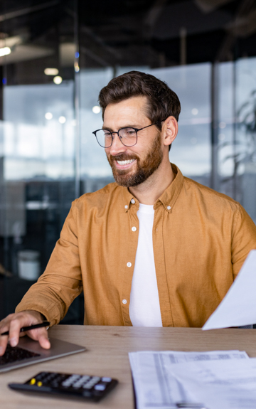 Ein Mann sitzt in einem Büro und tippt auf seinem Laptop.
